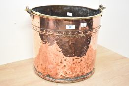 A large late 19th to early 20th-century copper and brass fireside bucket, having a hand riveted body