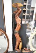 A tall 20th-century African Tribal Art hand-carved hardwood statue of a female drinking from a