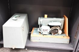 A vintage Singer electric table-top sewing machine, having a metal body upon a wooden base, in the