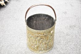 A large 20th-century brass and copper fireplace bucket, featuring embossed tavern-like scenes to