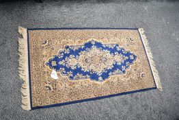 A small area rug in blue and gold fine ornate design, having a central medallion and fringed edging,