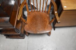 A 19th/20th century elm seated spindle back armchair, of traditional design with one-piece solid