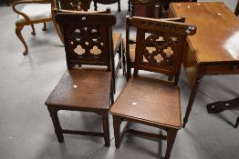 A matched pair of 19th Century Gothic style oak hall or dining chairs having solid seats, one having