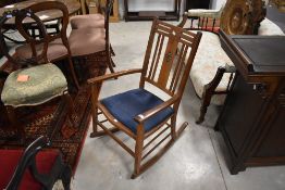 An Arts and Crafts golden oak rocking chair having inlaid petal heart decoration (one inlay missing)