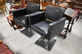 A pair of black vinyl and chrome hairdressing salon style armchairs with pump adjustable height
