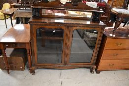 A late 19th or early 20th Century mahogany bookcase having mirrored ledge back with figural supports