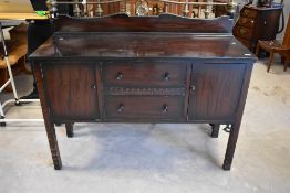 An early 20th Century dark stained sideboard having two central drawers flanked by cupboards,