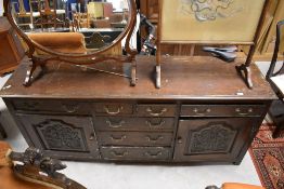 A period oak dresser base having multi drawer and cupboard arrangement, with carved doors,