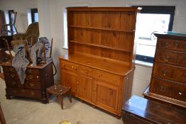 A vintage yellow pine kitchen dresser having delft rack over triple drawer and cupboard base,