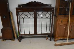 An early 20th Century mahogany display cabinet having glass shelves and papered interior, with