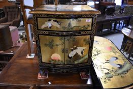 A modern Oriental bedside/occasional cabinet having ebonised and giltwork finish with pictorial