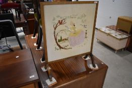 A late 19th or early 20th Century oak framed fire screen having embroidered panel inset