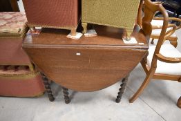 An early 20th century barley twist oak gate legged table, of traditional design with oval flaps, and