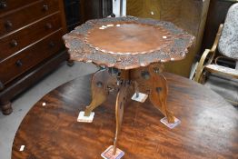 An Oriental style (believed to be Burmese) table having shaped and foliate carved top, on folding