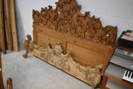 A traditional pine bed having extensively carved head and foot, width approx.153cm (five feet),