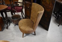 A 1950's upholstered accent chair, the flared and concaved back over a circular sprung seat,