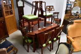 An Oriental hardwood extending dining table in the Chinese style and a set of six similar dining