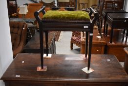 An Edwardian stained mahogany piano stool, with hinged and padded box seat between turned handles,