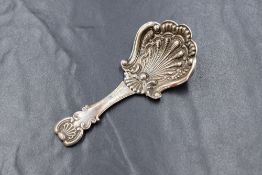 A George IV silver caddy spoon, having a scalloped scroll bowl with scroll and shell decoration to