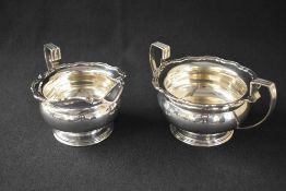 A George V silver sugar and cream, of bulbous form having Chippendale style rims with angular