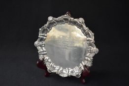 A George V silver presentation salver, having a shell and scroll rim with a central personalised