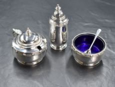 A George V silver three piece silver cruet set, comprising salt, mustard and pepperette, having a