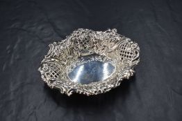 An Edwardian silver dish, of oval form having a decorative scroll rim, with further floral scroll