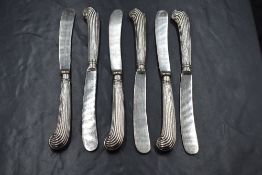 A set of six George V silver handled butter knives, having thread scroll decoration handles, marks
