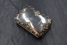 An Edwardian silver purse, of hinged rectangular form having embossed scroll decoration and blue