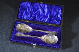 A cased pair of late Edwardian silver preserve spoons, having floral engraving to the bowls and