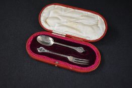 A cased George V silver Christening set, comprising a spoon and fork with ornate terminals, marks