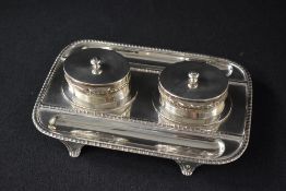 A Victorian silver ink stand, of rectangular form having a gadrooned rim with two oval ink wells