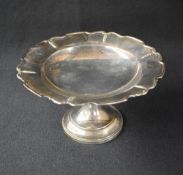 A George V silver pedestal bowl, having a Chippendale style rim with foliate decoration, raised on a
