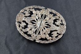 An Elizabeth II silver belt buckle, having a central sun motif within a laurel wreath having