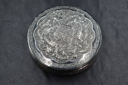 An Eastern white metal powder pot, of circular form having ornate flora and fauna decoration to