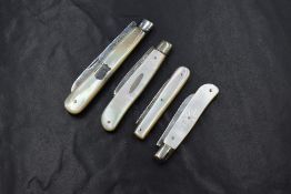 A group of four silver and mother-of-pearl fruit knives, two having silver inlays, one of plain form