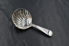 A George III silver caddy spoon, having a scalloped bowl with bright cut style engraving to
