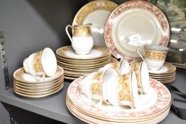 A Noritake 75th Anniversary part dinner service featuring gold flowers and scrolls on a tan marble