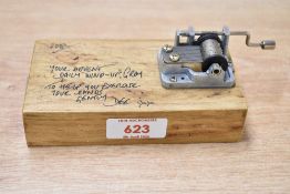 A contemporary handmade, palm size wooden music box, featuring a visible hand crank mechanism that