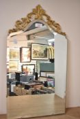 A late 20th century wall mirror having metal crested decoration, bevelled glass and painted wooden
