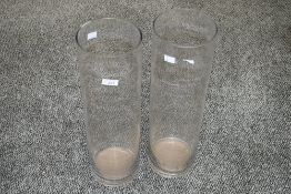 Two tall contemporary studio glass vases, off a slender cylindrical form, pontil mark to base,
