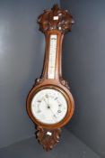 A tall Victorian carved oak aneroid banjo-style barometer, featuring decorative scrolled foliage