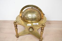 A 20th-century brass astrological world globe, mounted on a stand featuring zodiac signs and all
