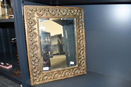 A late 19th to early 20th-century brass wall mirror, having a hand-embossed brass frame in the