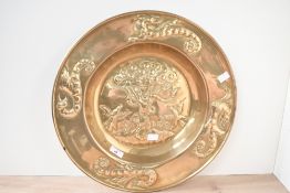 A large 20th-century Arts and Crafts-style decorative brass charger, featuring embossed religious