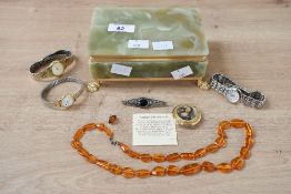 A green onyx jewellery box, having a small assortment of costume jewellery including amber bead