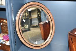 A vintage oval framed wooden mirror, having a wide rim, bevelled glass and gilt detailing, unmarked,