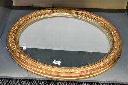 A 20th-century large oval ornate mirror having a gilt-frame of repeating leaf design two wall