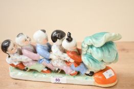 A vintage Chinese porcelain figurine, depicting five traditionally dressed children harvest a