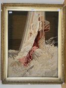 A framed woolwork tapestry depicting a lady draped in cloths, in brown, pink and taupe shades, in